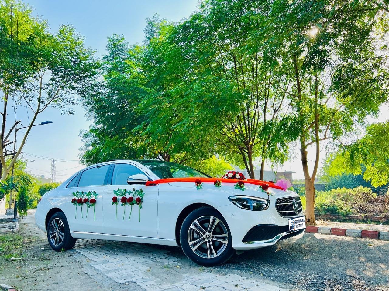 White Mercedes-Benz E-Class with roses on the doors and an orange ribbon on the bonnet