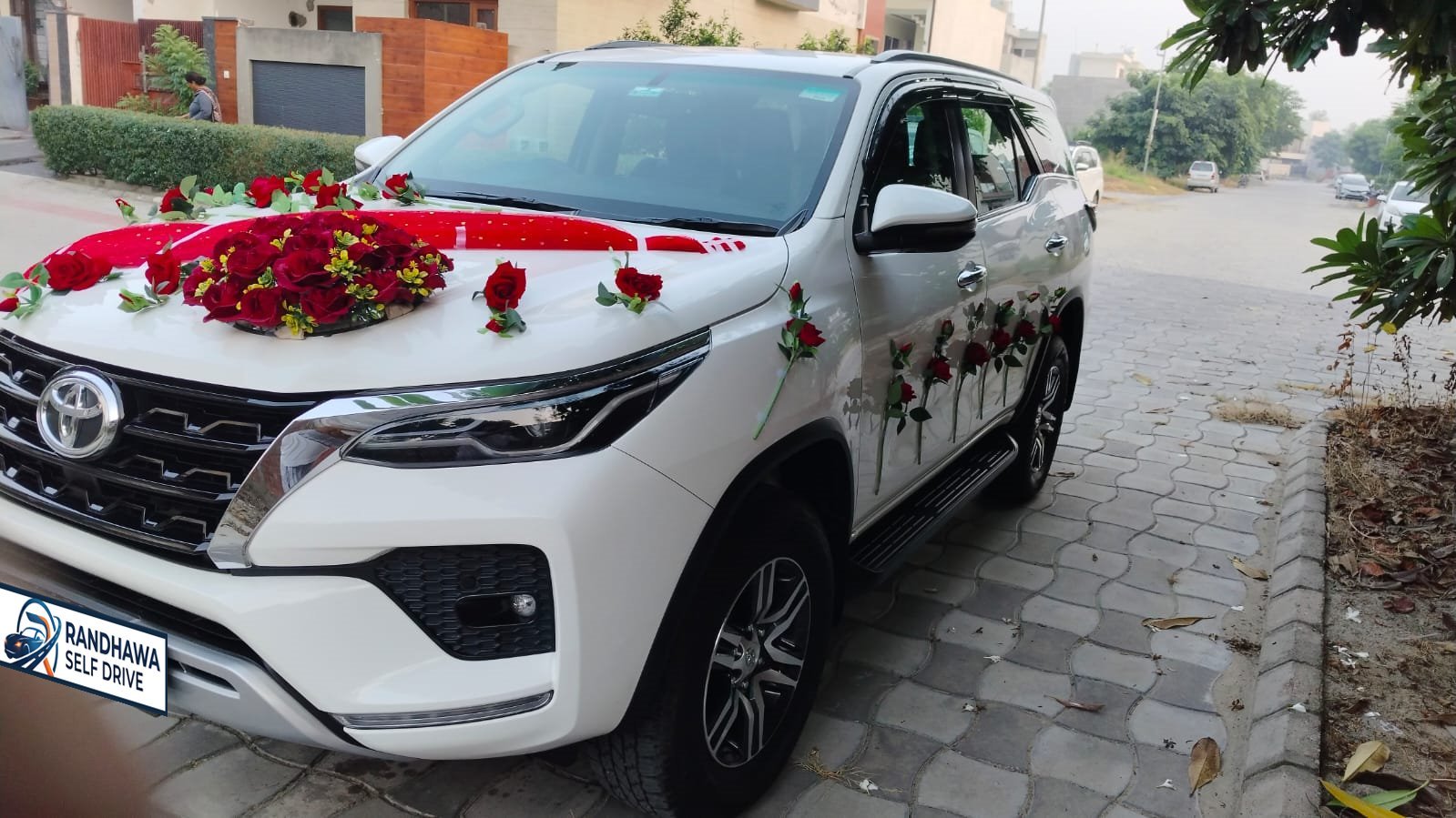 White Toyota Fortuner decorated with red roses and a red bonnet drape